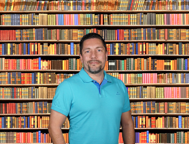 Michael Annas vor einem großen Bücherregal: Wissenswertes über körperliche und psychische Symptome